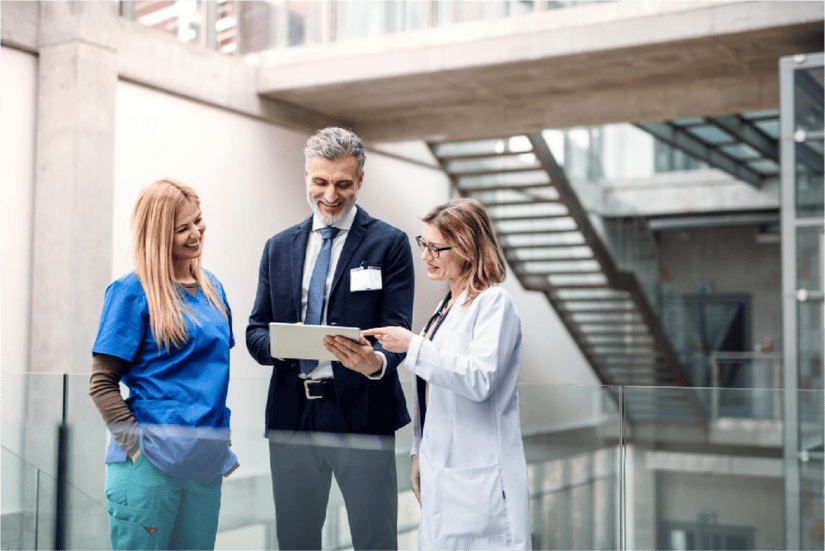 Medical professionals collaborating around a table with laptops and documents